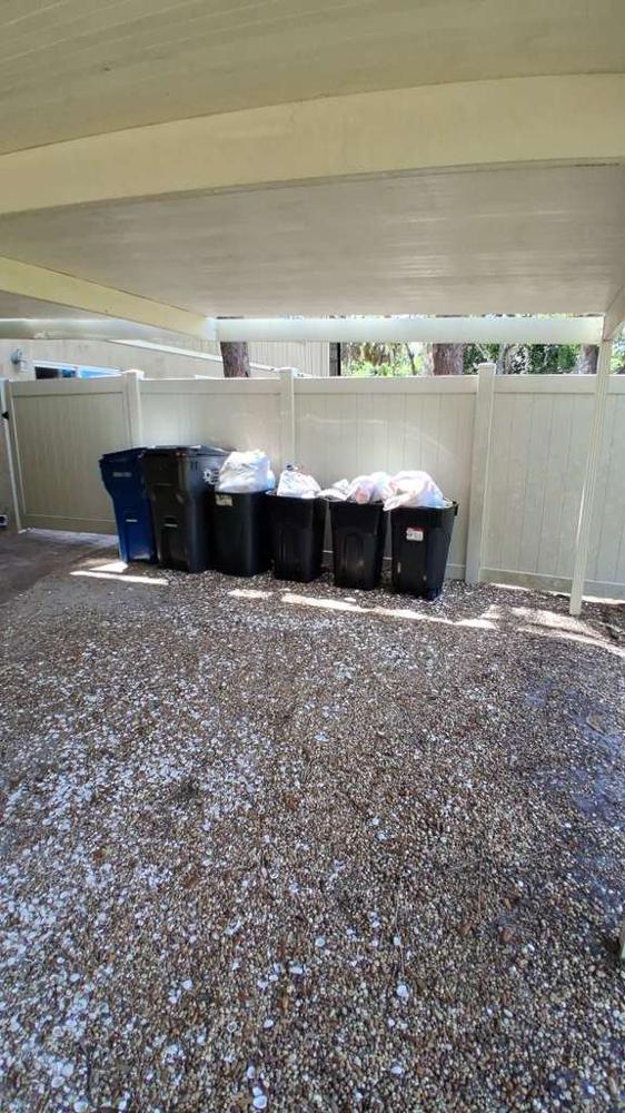 Botes de basura y reciclaje bajo un carport después de una limpieza