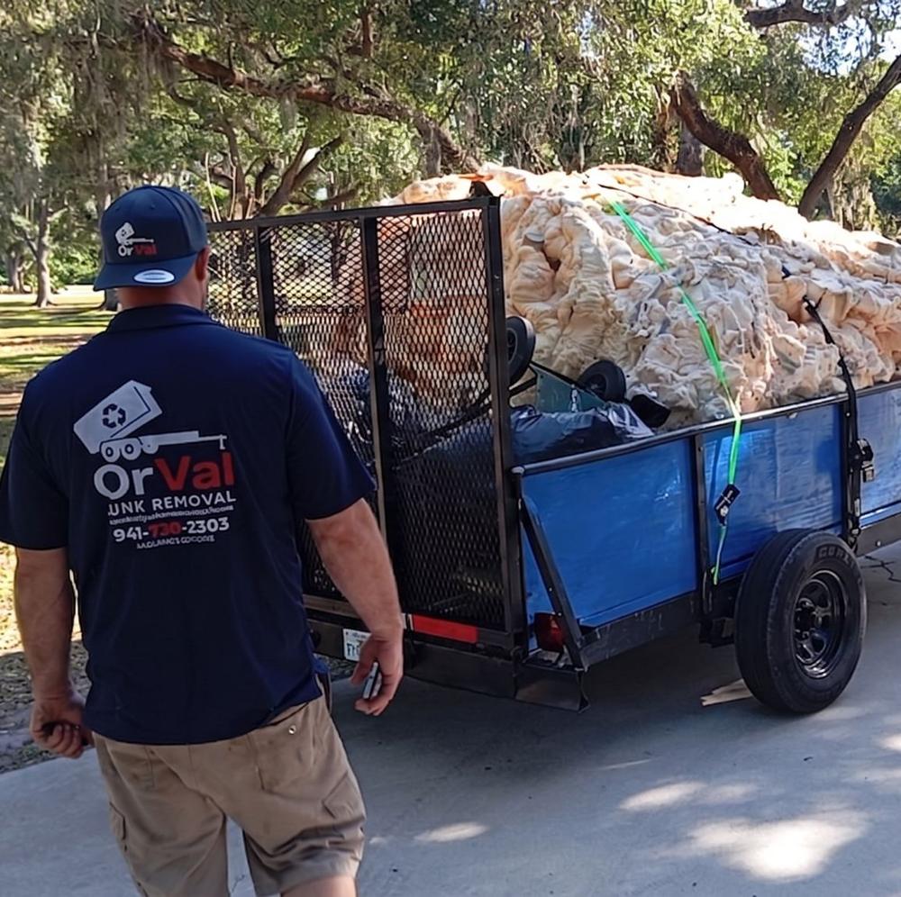 Orval crew member next to a trailer loaded with junk